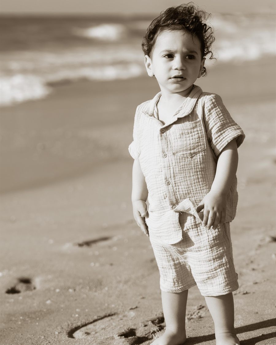 Sepia-toned portrait of a child standing on the beach.