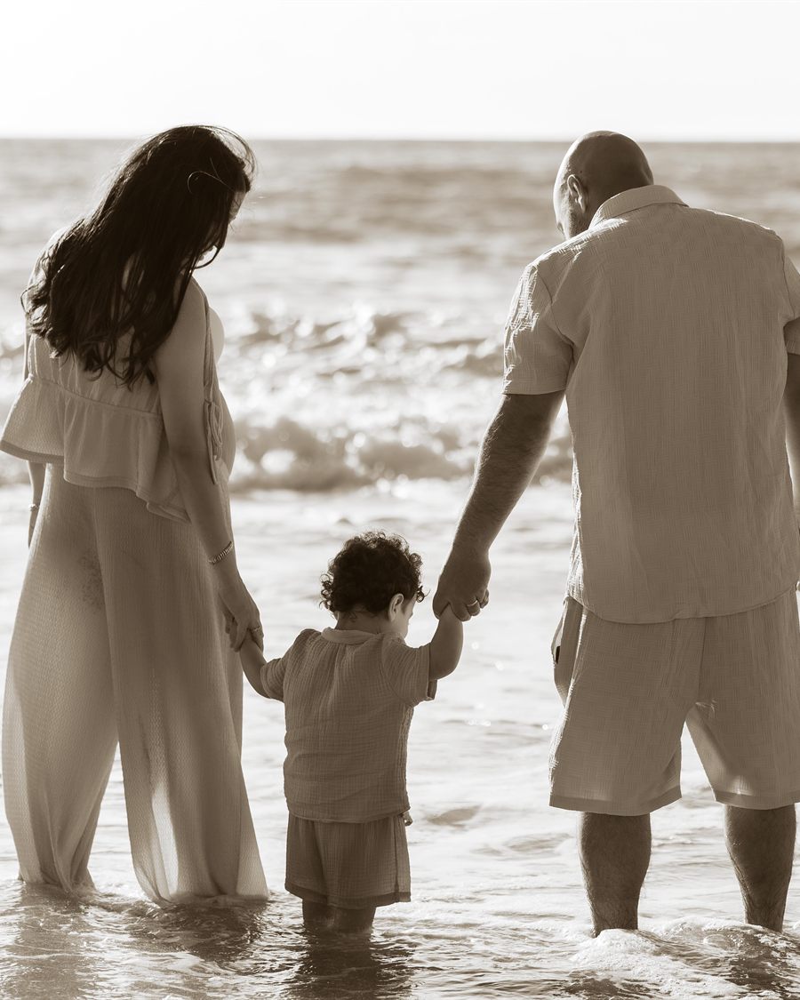 Family holding hands while standing together in the sea.